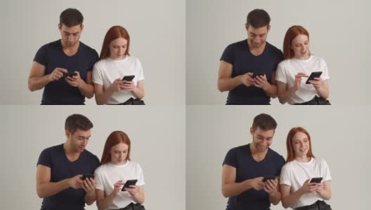 工作室肖像的年轻男子显示有趣的视频在智能手机上快乐的女朋友站在白色孤立的背景。沉迷于手机的情侣用手机看屏幕，慢动作。高清在线视频素材下载