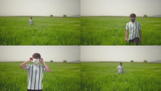 年轻男子穿着便服，在绿色的田野里散步，戴上防护口罩，遮住嘴和鼻子。高清在线视频素材下载