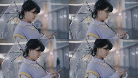 美丽的日本女性站在雨后的街道上使用智能手机高清在线视频素材下载