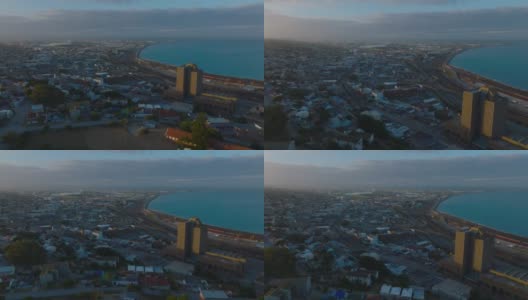 在夕阳照耀下的邮政高层建筑周围飞翔。海湾城市的航拍画面。南非伊丽莎白港高清在线视频素材下载