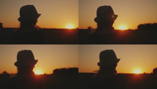 一个戴着帽子的孤独女人看着夕阳。后视图。梦想和规划一个概念高清在线视频素材下载