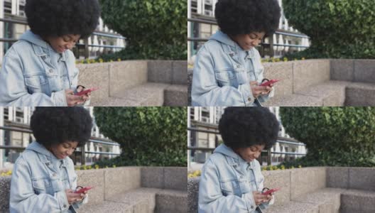 年轻的非裔美国妇女坐在户外使用手机高清在线视频素材下载