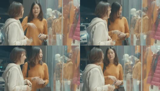 两个年轻的亚洲女人看着商店的橱窗，慢镜头高清在线视频素材下载