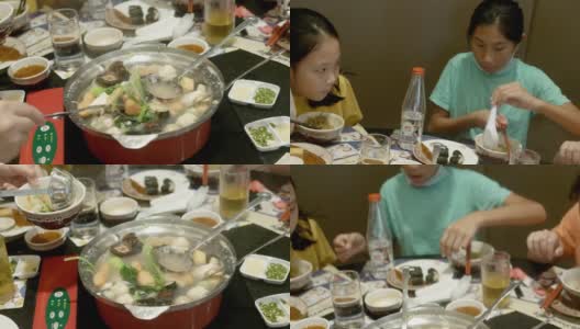 快乐的亚洲儿童与家人一起在餐厅吃素喜烧、涮涮锅或火锅，生活方式理念。高清在线视频素材下载