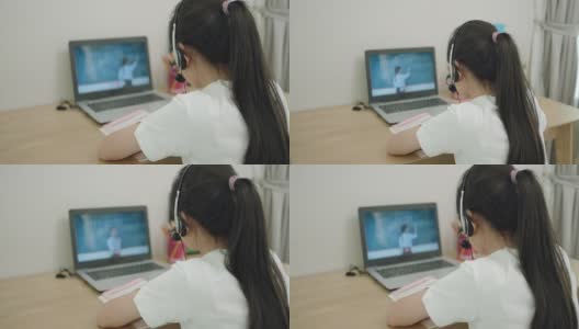 一名亚洲少女在学校因新冠肺炎疫情关闭期间，在家中的客厅通过笔记本电脑与老师在线学习数学。高清在线视频素材下载
