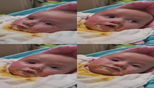宝宝吃东西，弄得一团糟。三个月大的婴儿在吃晚饭。看着摄像机。高清在线视频素材下载