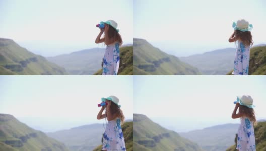 一个小女孩戴着帽子，穿着背心裙，通过望远镜在高山上观看——旅游，环保意识。爬山，积极的生活方式。达吉斯坦,Khunzakh高清在线视频素材下载