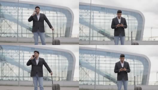 阿拉伯男子站在机场门口，在手机上查看他的航班时间表高清在线视频素材下载