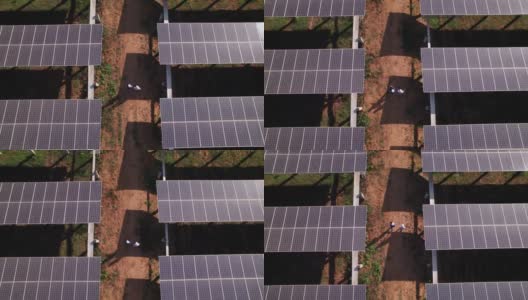 鸟瞰图，工程师和技术人员行走和检查太阳能电池板农场的影子，太阳能电池板，电力，太阳能产生的清洁能源高清在线视频素材下载