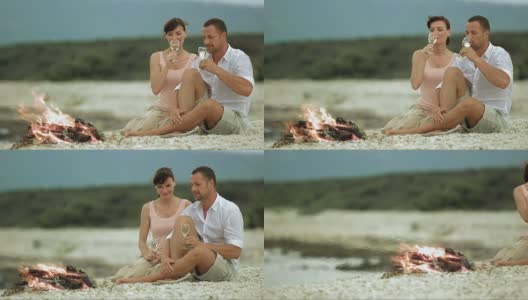 SLO MO夫妇在海滩上篝火旁祝酒高清在线视频素材下载