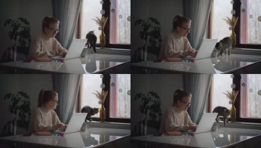 一个年轻女孩在家里工作或学习的时候在笔记本电脑上打字高清在线视频素材下载