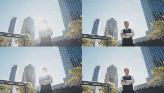 亚洲中国公司首席执行官双臂交叉站在城市办公楼的屋顶上，上午望向别处高清在线视频素材下载