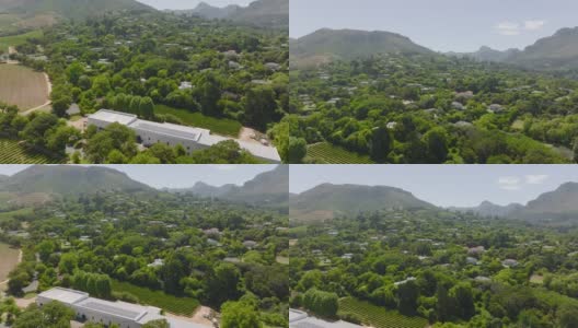 在绿树环绕的住宅区或村镇上空飞行。向上倾斜，在背景中显示山脉。南非开普敦高清在线视频素材下载