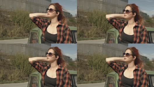 一个红发女人坐在汽车引擎盖上高清在线视频素材下载