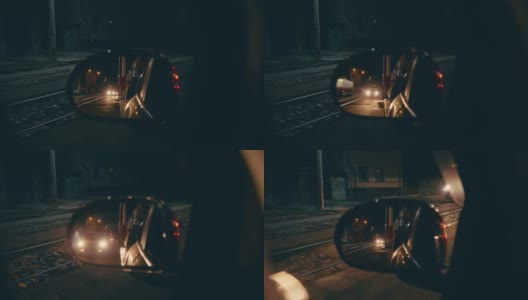 在一个欧洲小城市的夜晚，一辆经过的有轨电车在停着的汽车的后视镜里的倒影高清在线视频素材下载