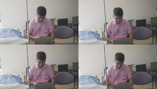 一个亚洲病人在医生的候诊室用笔记本电脑工作高清在线视频素材下载