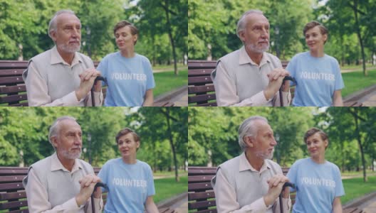 善良的志愿者支持一位悲伤的老人，坐在公园的长椅上，帮助他高清在线视频素材下载