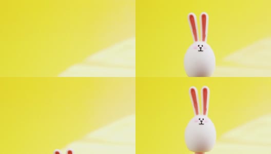 有趣的复活节兔子玩具，耳朵在复活节蛋的形状，在黄色的背景与阳光，出现和消失。复活节的概念。高清视频高清在线视频素材下载