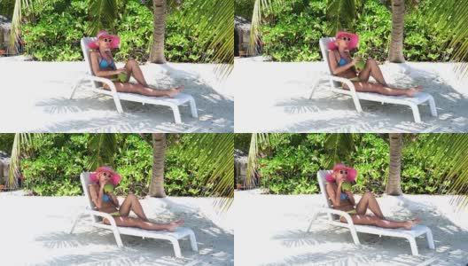 一名嬉皮士女子坐在马尔代夫的棕榈树下喝椰子汁高清在线视频素材下载