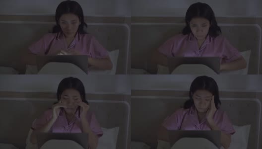 疲惫的女人在黑暗的卧室里用笔记本电脑工作高清在线视频素材下载