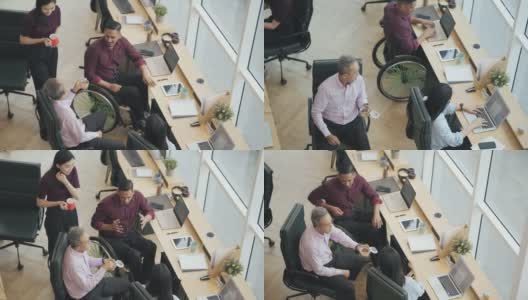 亚洲残疾白领在休息时间与同事一起在办公室吃零食高清在线视频素材下载