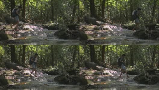 夏季，亚洲女性徒步旅行者背着双肩包，在美丽的热带森林中穿过流过岩石的溪流。高清在线视频素材下载