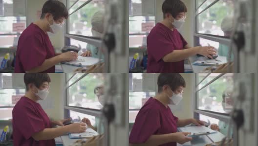 亚裔华裔老年妇女戴着口罩，在诊所用信用卡刷卡，女护士拿着信用卡读卡器高清在线视频素材下载