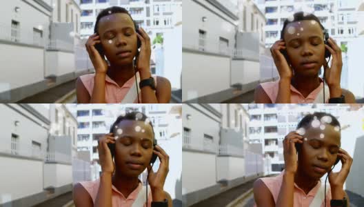美丽的非洲裔美国人在城市的街道上用耳机听音乐高清在线视频素材下载
