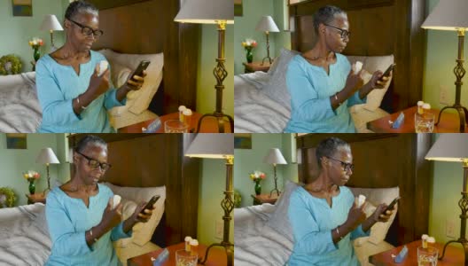 一个非裔美国女性在用智能手机看药瓶高清在线视频素材下载