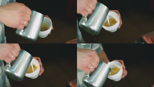 咖啡师将牛奶倒入咖啡杯中，制作拉花艺术。慢动作镜头。高清在线视频素材下载