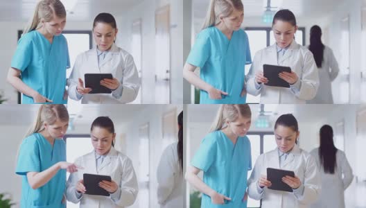 在医院里，忙碌的医生在走廊里一边聊天一边使用平板电脑。新型现代化、功能齐全的医疗设施。高清在线视频素材下载