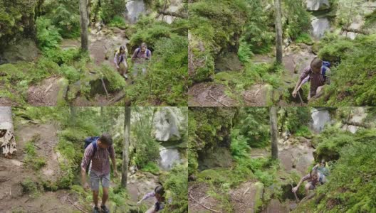 俯视图:一名男子帮助一名女子爬上陡峭的小路。在森林里徒步旅行高清在线视频素材下载