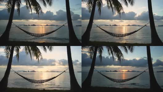 日出的海边有两棵棕榈树和吊床。间隔拍摄。高清在线视频素材下载