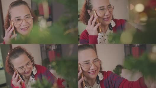 亚洲老女人喜欢在家里装饰圣诞树和打电话。高清在线视频素材下载