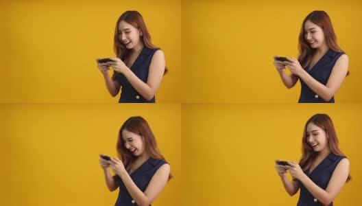 亚洲女性玩家在智能手机上玩在线游戏，黄色背景，娱乐与令人敬畏的应用概念高清在线视频素材下载