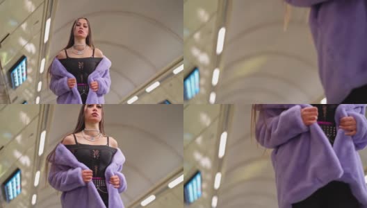 穿着紫色合成皮草大衣的时尚模特女孩慢镜头走在地铁或地铁站台上。女性奢华的化妆，长发和时尚的服装高清在线视频素材下载