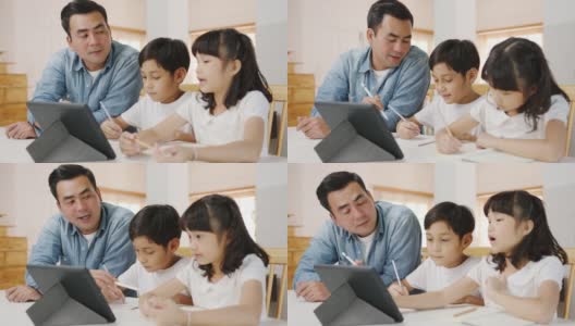 快乐亚洲家庭家庭教育，爸爸在家里的客厅教孩子使用数码平板电脑。高清在线视频素材下载