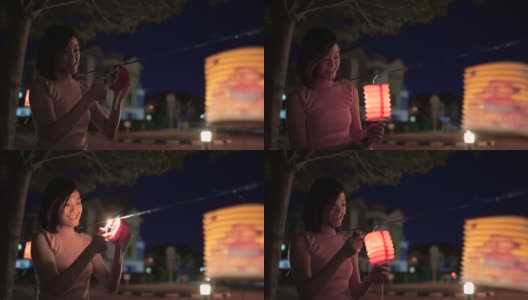 亚洲华人妇女在纸灯笼里点燃蜡烛，庆祝中秋节。高清在线视频素材下载