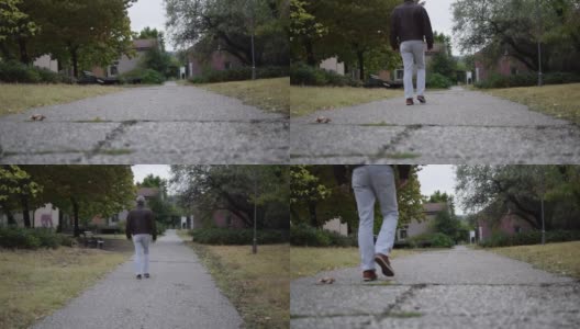 高清库存视频的一个背影，高级男子穿着皮夹克在公园的人行道上散步，天气阴沉。高清在线视频素材下载
