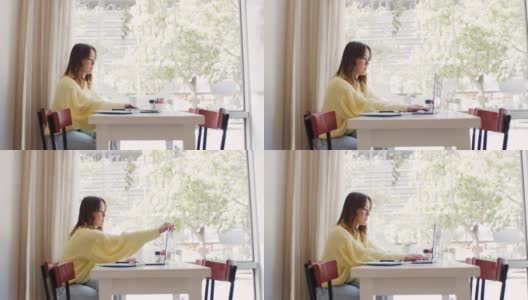 一个年轻女子坐在咖啡店里打开笔记本电脑的4k视频片段高清在线视频素材下载