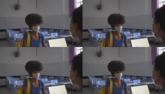一名十几岁的学生戴着口罩在教室里与老师交谈高清在线视频素材下载