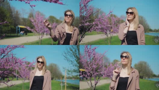 春天，美丽的女人在公园里散步，欣赏粉红色的樱花高清在线视频素材下载