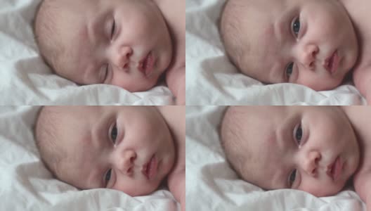 新生儿在白色毯子上的特写肖像。软的焦点。婴儿侧身躺着。1、2周大。小女孩在家里的床上醒来。新的生活和成长观念。真实的人。高清在线视频素材下载