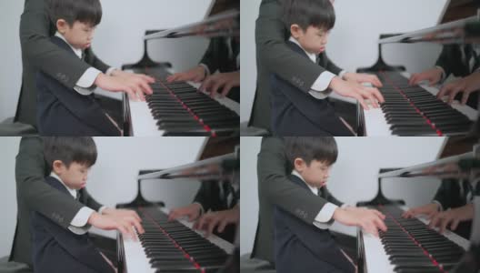 钢琴家在学校的教室里教一个男孩弹钢琴。最喜欢的古典音乐。在学习中快乐和乐趣。身着正式优雅套装的音乐家。教育、练习、放松的理念。高清在线视频素材下载