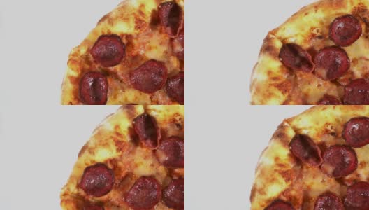 一个美味的意大利辣香肠披萨在桌子上旋转的微距镜头，孤立在白色背景上高清在线视频素材下载