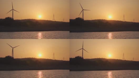 在印度古吉拉特邦的万卡纳，夕阳西下，风车在河边的山丘上拍摄剪影。在黄金时段，除了太阳，还能看到风车和电塔。自然日落背景。高清在线视频素材下载