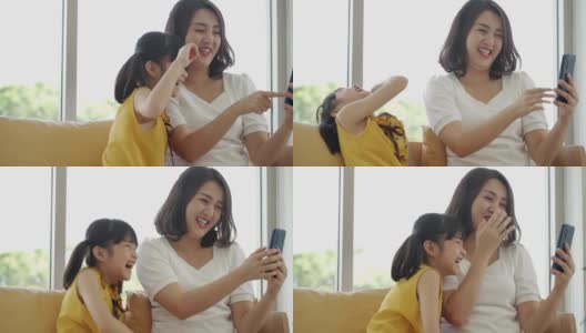 多利拍摄，亚洲妈妈和女儿一起在客厅玩智能手机高清在线视频素材下载