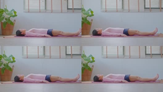 平静的亚洲妇女练习瑜伽死尸或Savasana姿势与冥想微笑在家里感觉如此舒适和放松，保健概念高清在线视频素材下载