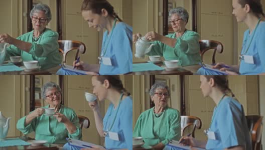 年长的妇女和家庭看护聊天，在家喝茶。高清在线视频素材下载