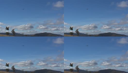 一架军用直升机在蓝天上飞行，天空中有蓬松的云朵和灰色高清在线视频素材下载